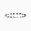 The Lab Grown Blue and White Diamond Multi Shape Tennis Bracelet in 14K White Gold showcases alternating oval, round, and emerald-cut lab-grown blue and white diamonds against a white background.