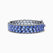The Nahla Siri Sterling Silver Tanzanite and Diamond Bracelet features three rows of oval-cut tanzanite gemstones in prong settings on an intricate, reflective sterling silver band, displayed against a white background.