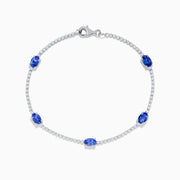 The Nahla Siri 14K White Gold Tanzanite and Diamond Tennis Bracelet features five oval tanzanite gemstones set among sparkling diamond accents in a delicate design with a secure clasp.