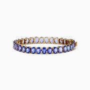 The Nahla Siri 14K Yellow Gold Tanzanite Tennis Bracelet showcases a continuous row of oval-cut blue gemstones set closely together for an elegant look.
