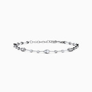 The 14K White Gold Diamond Station Bracelet features small round and teardrop-shaped diamonds spaced along a thin chain, showcased on a white background.