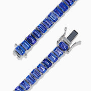 The Nahla Siri Sterling Silver Emerald Cut Tanzanite Tennis Bracelet, featuring a row of individually prong-set gemstones, is elegantly displayed on a plain white background.