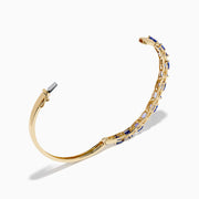 The Nahla 14K Yellow Gold Tanzanite and Diamond Bangle features alternating triangular tanzanite stones and sparkling diamonds in a repeating pattern along the gold band.