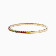 The Watercolors 14K Yellow Gold Multi Sapphire Bangle features a slim yellow gold band adorned with a row of rainbow-hued sapphires along the outer edge, shown on a white background.