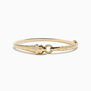 The Signature 14K Yellow Gold Diamond and Tsavorite Bangle features a panther’s head with tsavorite eyes, sparkling stones along the band, and a gem-encrusted circular link clasped in its mouth.