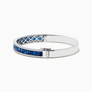 The Royale Bleu 14K White Gold Blue Sapphire and Diamond Bangle showcases a row of rectangular blue sapphires bordered by sparkling diamonds, elegantly set against a white background.
