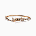 The Signature 14K Rose Gold Diamond and Emerald Panther Bangle features a panther design with its head and tail meeting at the front, adorned with sparkling diamonds and emeralds.