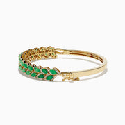 The 14K Yellow Gold Emerald and Diamond Marquise Leaf Bangle showcases an intricate leaf design with alternating emeralds and diamonds set along the band.