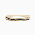 The 14K Yellow Gold Black and White Diamond Crossover Bracelet features overlapping bands adorned with rows of sparkling black and white diamonds, creating an elegant, multi-layered design.