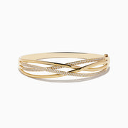The Doro 14K Yellow Gold Diamond Crossover Bangle features interwoven gold bands, some set with sparkling white diamonds, for a sophisticated, shimmering look.