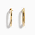 A pair of 14K Yellow Gold Hollow Round Hoop Earrings is shown on a white background, with soft shadows cast to the left.
