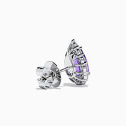 The 18K White Gold Purple Sapphire and Diamond Halo Earrings showcase teardrop-shaped purple sapphires encircled by sparkling diamonds, set against a white background.