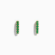 A pair of Brasilica 14K Yellow Gold Emerald Huggie Earrings is displayed against a plain white background.