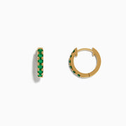 A pair of Brasilica 14K Yellow Gold Emerald Huggie Earrings is displayed against a plain white background.