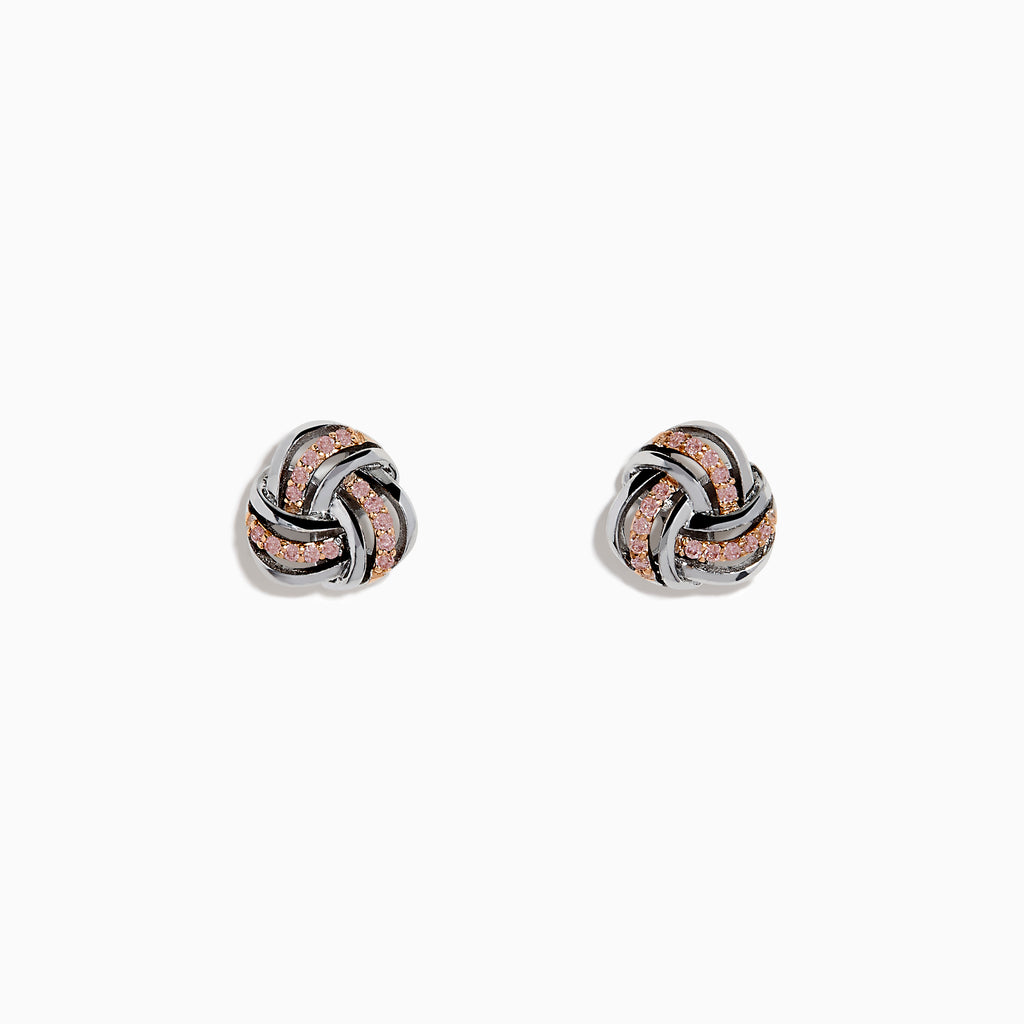 The 14K White Gold Pink Diamond Love Knot Earrings feature an intricate knot design in silver and rose gold tones, accented with sparkling pink diamonds. They are displayed against a plain white background.