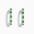Displayed against a white background, these 14K yellow gold hoop earrings feature alternating emerald and diamond gemstones (3.58 TCW), making for a striking and elegant pair.