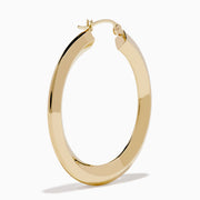 A pair of 14K Yellow Gold Rhombus Tube Hoop Earrings with a shiny, geometric shape, displayed on a white background.