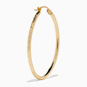 A pair of 14K Yellow Gold Oval Tube Baguette Cut Hoop Earrings, thin and textured, are displayed vertically with clasps at the top against a plain white background.