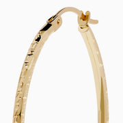 A pair of 14K Yellow Gold Oval Tube Baguette Cut Hoop Earrings, thin and textured, are displayed vertically with clasps at the top against a plain white background.