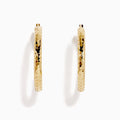 The 14K Yellow Gold Reverse Vibrant Cut Hoop Earrings feature a large, eye-catching design and are showcased against a plain white background with soft shadows.