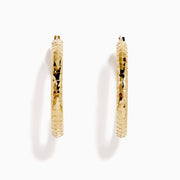 The 14K Yellow Gold Reverse Vibrant Cut Hoop Earrings feature a large, eye-catching design and are showcased against a plain white background with soft shadows.