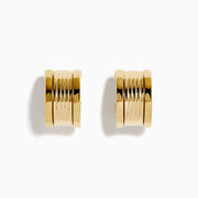 The 14K Yellow Gold Chunky Huggie Earrings feature a ridged, cylindrical design and are shown against a white background.