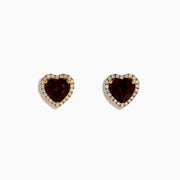 The 14K Yellow Gold Garnet and Diamond Halo Heart Stud Earrings feature deep red heart-shaped garnets at the center, each surrounded by a sparkling diamond halo, all set in yellow gold.