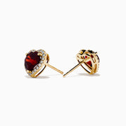 The 14K Yellow Gold Garnet and Diamond Halo Heart Stud Earrings feature deep red heart-shaped garnets at the center, each surrounded by a sparkling diamond halo, all set in yellow gold.