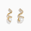 The 14K Yellow Gold Fresh Water Pearl and Diamond Ribbon Earrings feature a spiral gold design encrusted with small diamonds, elegantly encircling a large freshwater pearl, all showcased on a plain white background.