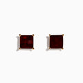 A pair of 14K Rose Gold Garnet Stud Earrings, featuring square-cut deep red garnets in gold prongs, displayed on a plain white background.