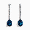 The 14K White Gold Blue Topaz and Diamond Linear Drop Earrings feature large teardrop-shaped blue topaz gems with a vertical row of round and rectangular diamonds set above each stone.