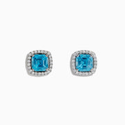 14K White Gold Blue Zircon and Diamond Stud Earrings featuring square-cut blue zircon stones, each encircled by a halo of sparkling diamonds, set on a white background.