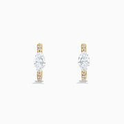 Lab Grown Diamond Marquise Huggie Earrings in 14K Yellow Gold, each showcasing a central round diamond and smaller accent diamonds along the vertical sides, displayed on a plain white background.