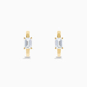 A pair of Lab Grown Diamond Emerald-Cut Huggie Earrings in 14K Yellow Gold is shown on a plain white background, each earring featuring a vertically set emerald-cut lab grown diamond at the center.