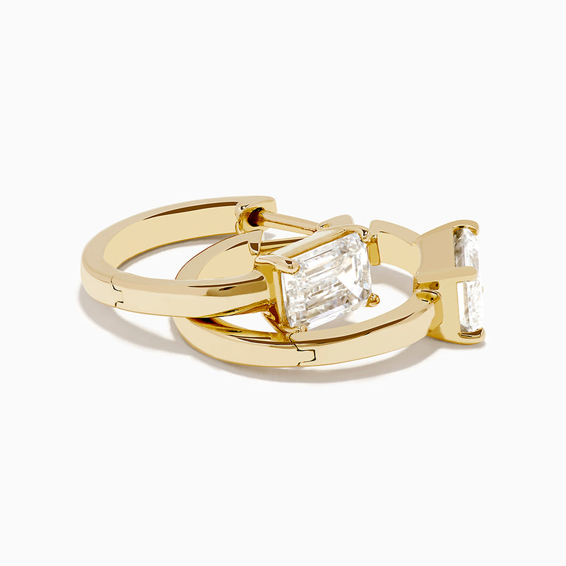 A pair of Lab Grown Diamond Emerald-Cut Huggie Earrings in 14K Yellow Gold is shown on a plain white background, each earring featuring a vertically set emerald-cut lab grown diamond at the center.