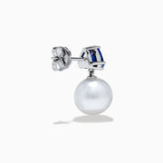The Nahla 14K White Gold Fresh Water Pearl and Tanzanite Earrings feature round white pearls suspended below triangular blue tanzanite gemstones, set in white gold, displayed on a white background.