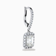 The Lab Grown Diamond Emerald Cut Dangle Earrings in 14K White Gold showcase emerald cut lab grown centers with a halo of round diamonds and diamond-encrusted hooks, elegantly presented against a white background.