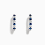 The 14K White Gold Sapphire and Diamond Hoop Earrings feature alternating round sapphires and diamonds, beautifully set and displayed on a white background.