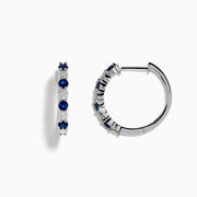 The 14K White Gold Sapphire and Diamond Hoop Earrings feature alternating round sapphires and diamonds, beautifully set and displayed on a white background.