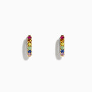 A pair of Watercolor 14k Gold Multi Sapphire Huggie Earrings featuring small gold hoops set with multicolored sapphires in a row, displayed on a plain white background.