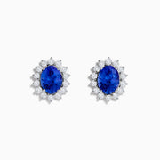 The Nahla Siri 14K White Gold Tanzanite and Diamond Earrings feature oval tanzanite stones surrounded by a halo of sparkling diamonds, elegantly set in white gold and displayed on a white background.