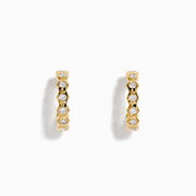 D'Oro 14K Yellow Gold Bezel Set Diamond Mini Hoop Earrings feature round diamonds in bezel settings along the front, alternating with gold, shown on a white background.