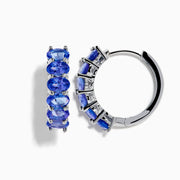 The Nahla Siri 925 Silver Tanzanite Hoop Earrings feature five oval tanzanite gemstones in prong settings, elegantly crafted from sterling silver and showcased against a plain white background.