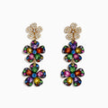 The Watercolors 14K Yellow Gold Multi Sapphire Flower Earrings feature three-tiered sapphire petals outlined in gold, attached to a gold flower stud adorned with sparkling clear crystals.