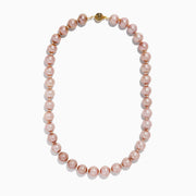 A close-up of the 14K Yellow Gold Freshwater Lilac Pearl Necklace highlights its round, glossy lilac pearls elegantly strung together in a gentle curve against a white background.