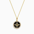 The Novelty 14K Yellow Gold Black Onyx, White and Black Diamond Compass Pendant features a gold chain and round compass design with sparkling stones, shown against a plain white background.