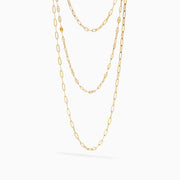 The 14K Yellow Gold Layered Chain Necklace features three delicate chains of different lengths with evenly spaced links, displayed on a white background—a perfect set for achieving effortless elegance.