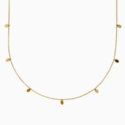 The 14K Yellow Gold Oval Charm Station Necklace features small, evenly spaced oval-shaped charms that hang gracefully along the lower half of a delicate yellow gold chain.