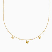 The 14K Yellow Gold Butterfly Station Necklace features three butterfly charms and four round beads evenly spaced along a delicate chain.