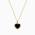 The 14K Yellow Gold Onyx and Diamond Heart Pendant features a glossy black onyx center surrounded by sparkling diamonds, all set on a yellow gold chain necklace.